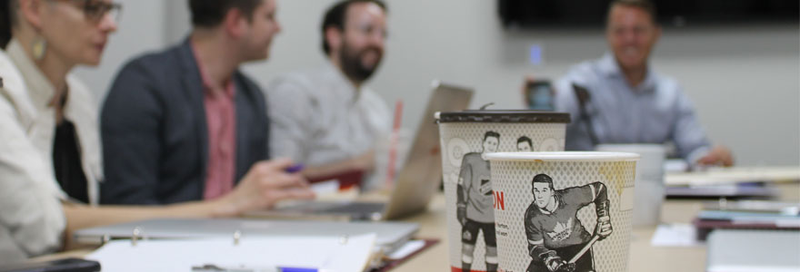 Coffee cups featuring hockey players, in foreground; researchers in backgroud